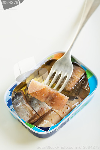 Image of Tin and slice of herring on a fork.