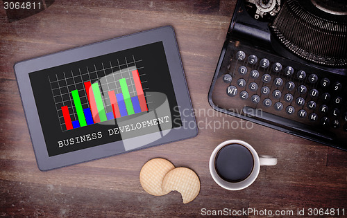 Image of Tablet touch computer gadget on wooden table, graph