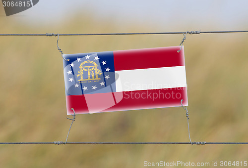 Image of Border fence - Old plastic sign with a flag