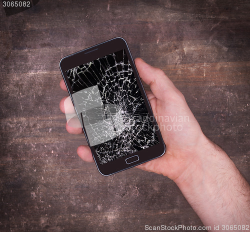 Image of Hand holding a mobile phone with a broken screen