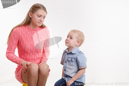 Image of Young mother reproachfully looks at his young son