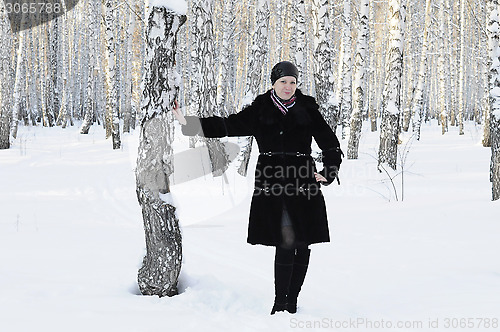 Image of The woman in a black fur coat costs in the birch wood in the win