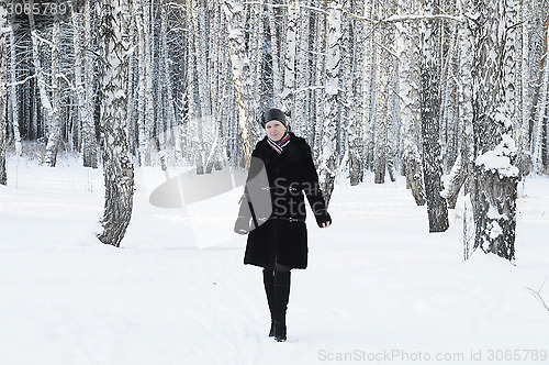 Image of The woman in a black fur coat costs in the birch wood in the win