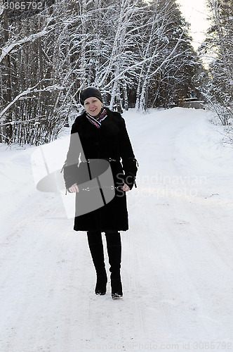 Image of The woman in a black fur coat costs in the birch wood in the win