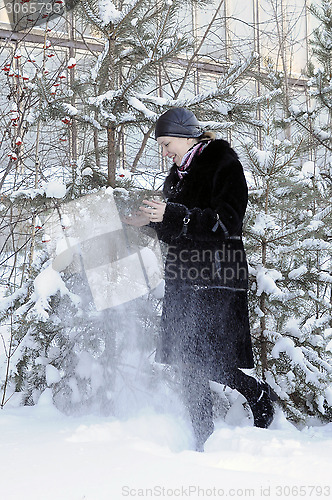 Image of The cheerful woman in a black fur coat costs at snow-covered pin