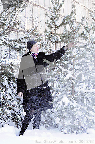 Image of The cheerful woman in a black fur coat costs at snow-covered pin