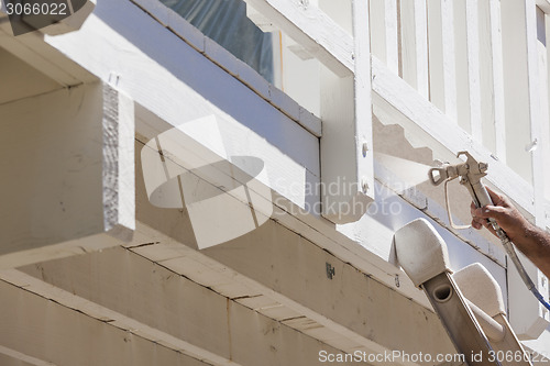 Image of House Painter Spray Painting A Deck of A Home