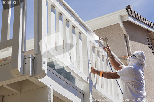 Image of House Painter Spray Painting A Deck of A Home