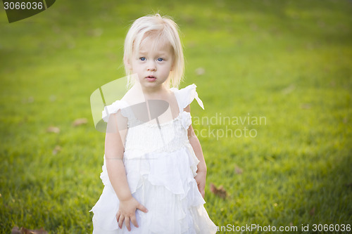 Image of Adorable Little Girl Wearing White Dress In A Grass Field