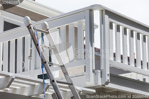 Image of Construction Ladder and Painting Hose Leaning on House Deck