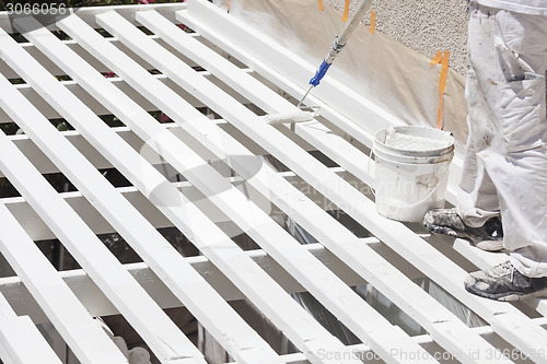 Image of Painter Rolling White Paint Onto Top of Patio Cover