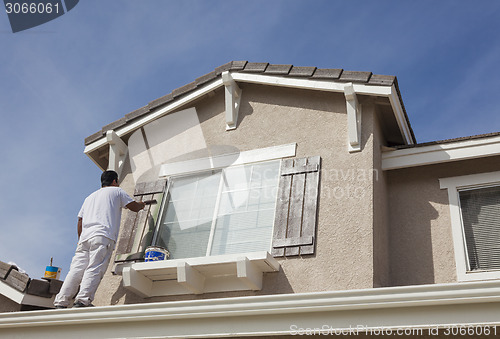 Image of House Painter Painting the Trim And Shutters of Home