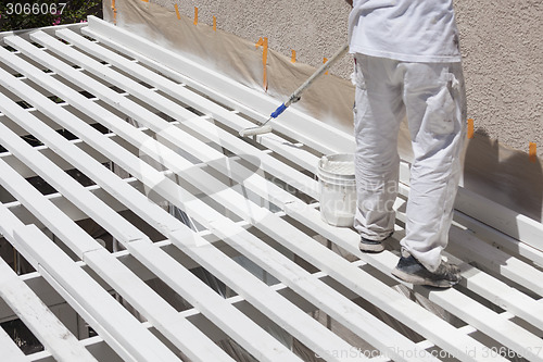 Image of Painter Rolling White Paint Onto Top of Patio Cover