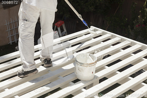 Image of Painter Rolling White Paint Onto Top of Patio Cover