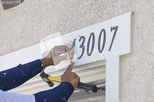 Image of House Painter Contractor Nails Address Numbers to House Facade