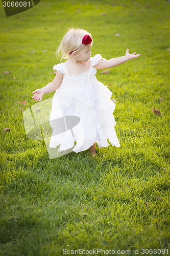 Image of Adorable Little Girl Wearing White Dress In A Grass Field