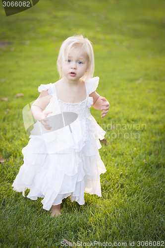 Image of Adorable Little Girl Wearing White Dress In A Grass Field