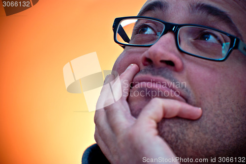 Image of Bearded caucasian man wearing eyeglasses looking up on orange gr