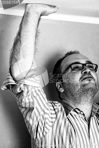 Image of man in striped shirt touching ceiling with hand