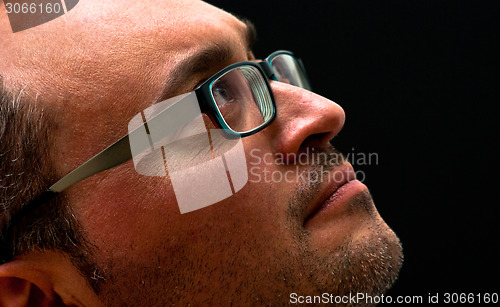 Image of bearded caucasian man wearing glasses looking up on black