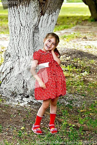 Image of Girl in red dress under tree in the park