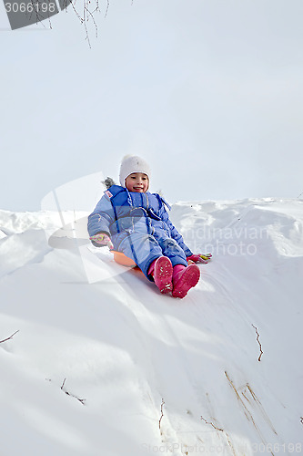 Image of Little girl rolling on a hill