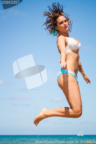 Image of Beautiful woman is jumping against blue sky