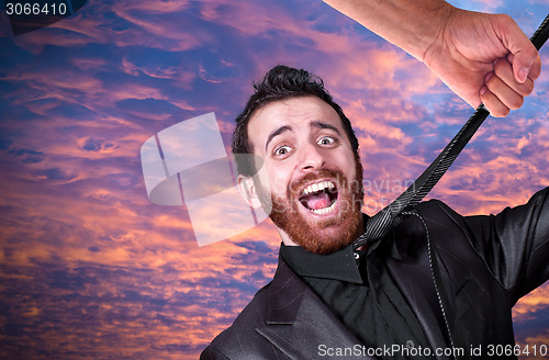 Image of Big hand grabbing the necktie of young businessman