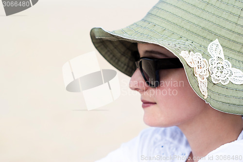 Image of Portrait of a beautiful young woman in sunglasses and green hat