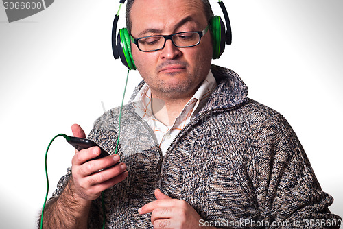 Image of man listening to music and looking at cell phone with puzzled lo