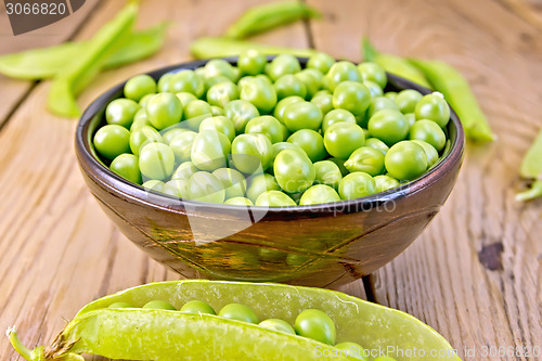 Image of Green peas in brown bowl and pod on board