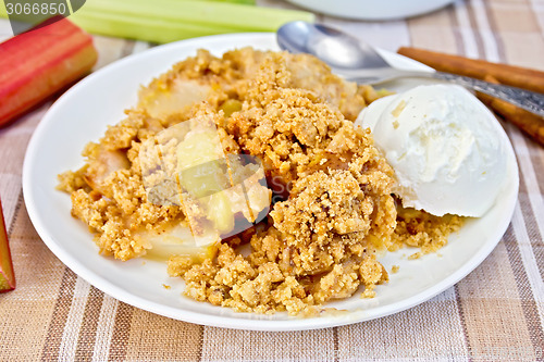 Image of Crumble with rhubarb and ice cream in bowl on linen tablecloth