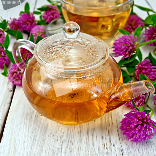 Image of Tea with clover in glass teapot on board