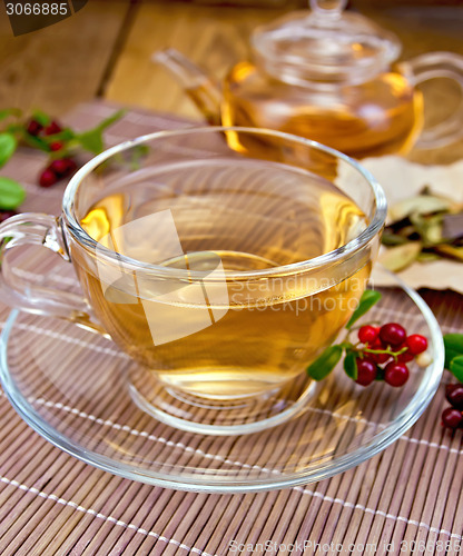 Image of Tea with lingonberry in glass cup on bamboo napkin