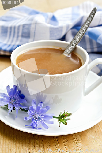 Image of Chicory drink in white cup with spoon and flower on board