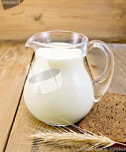 Image of Milk in glass jug with bread on board