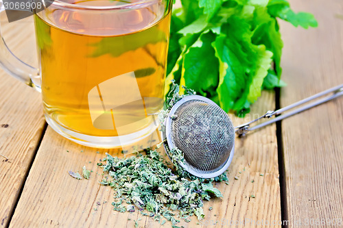 Image of Herbal tea with mint in mug with strainer on board