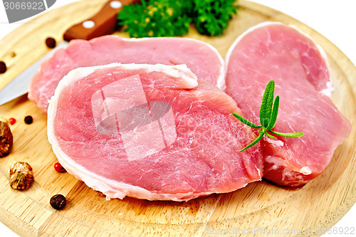 Image of Meat pork slices with rosemary on round board