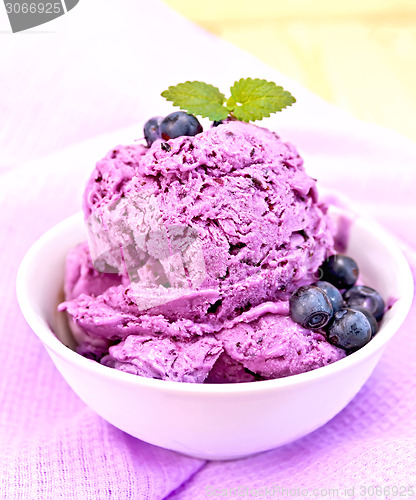 Image of Ice cream blueberry with mint in bowl on purple napkin