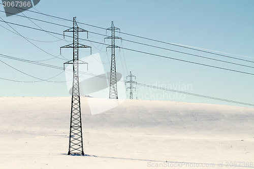 Image of High voltage electricity power pylon on snowy field