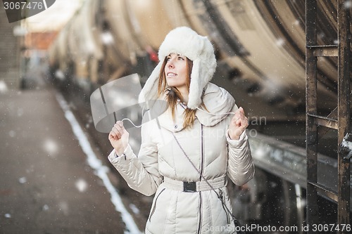 Image of Pretty girl in winter blizzard on railroad station