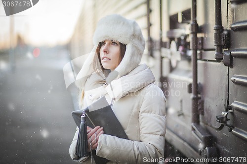 Image of Pretty girl in winter blizzard on railroad station