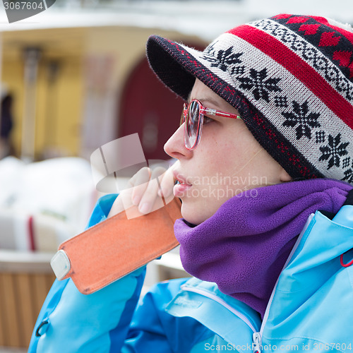 Image of Woman in ski resort using smartphone.