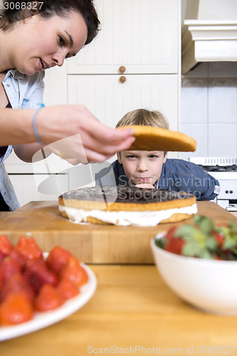 Image of Boy Looking At woman Preparing Cake