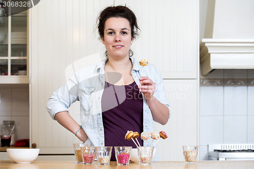 Image of Woman Holding Cupcake Pop In Kitchen