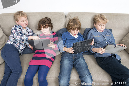 Image of Brothers And Sister Using Digital Tablets On Sofa