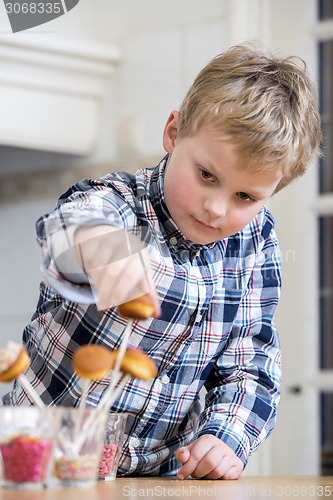 Image of Boy putting cupcake pop in glass