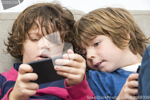 Image of Brother and sister Using Smart Phone On Sofa