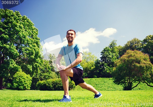 Image of smiling man stretching outdoors