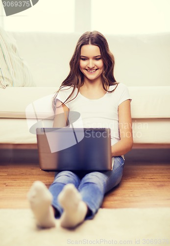 Image of smiling teenage girl with laptop computer at home